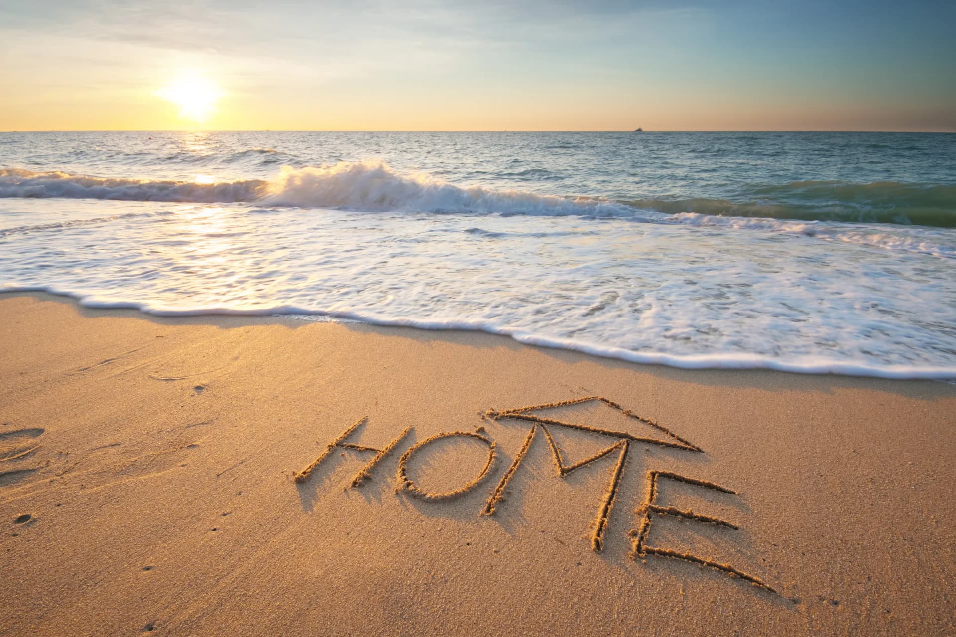 HOME written in the sand on a Gulf beach at sunrise